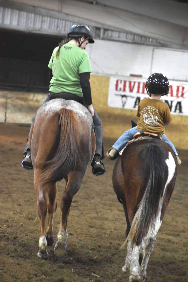 Two children on horses side by side at Civil War Arena